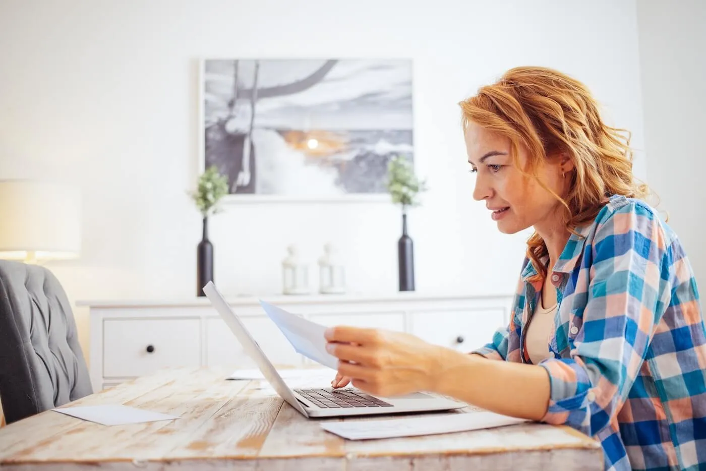 Smiling woman working on her finances at home with a laptop on the desk