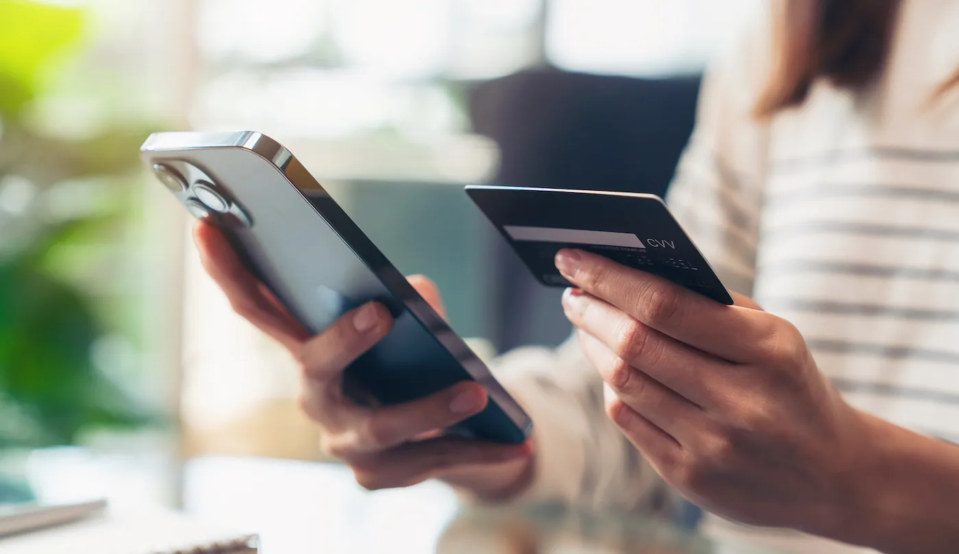 Hands holding credit cards and using smartphone to look at minimum credit card payment.