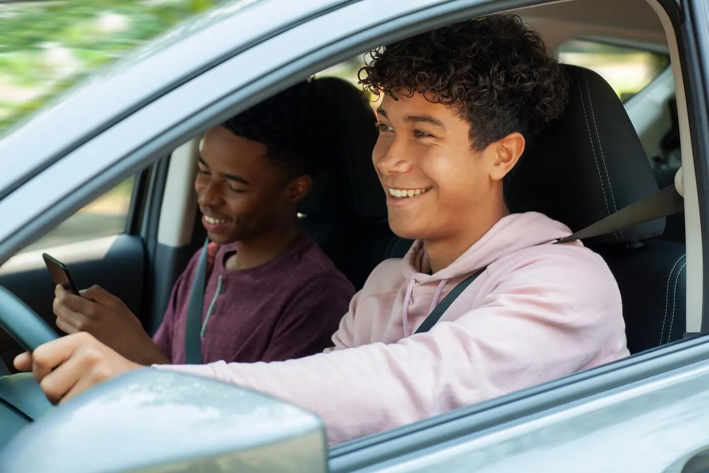 Young man driving a car with his friend on a passenger seat