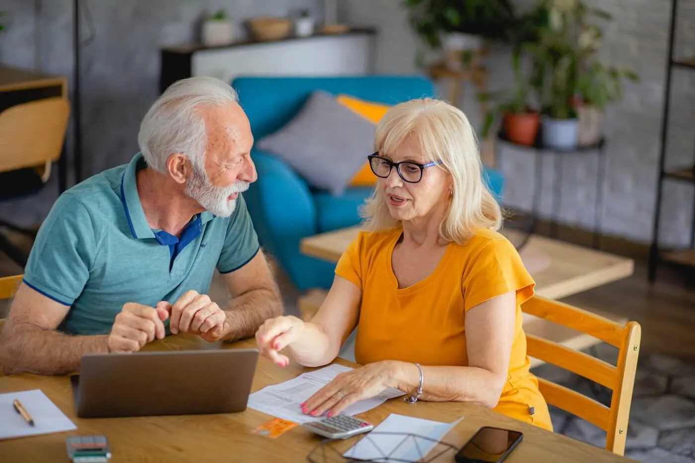 Senior couple discussing finances while using a laptop at home