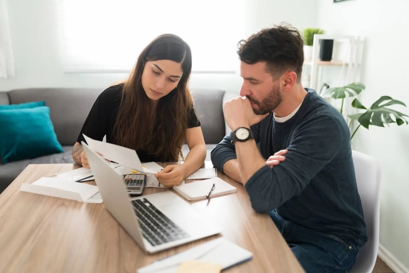 Focused couple discussing their finances with an open laptop on the table in the living room