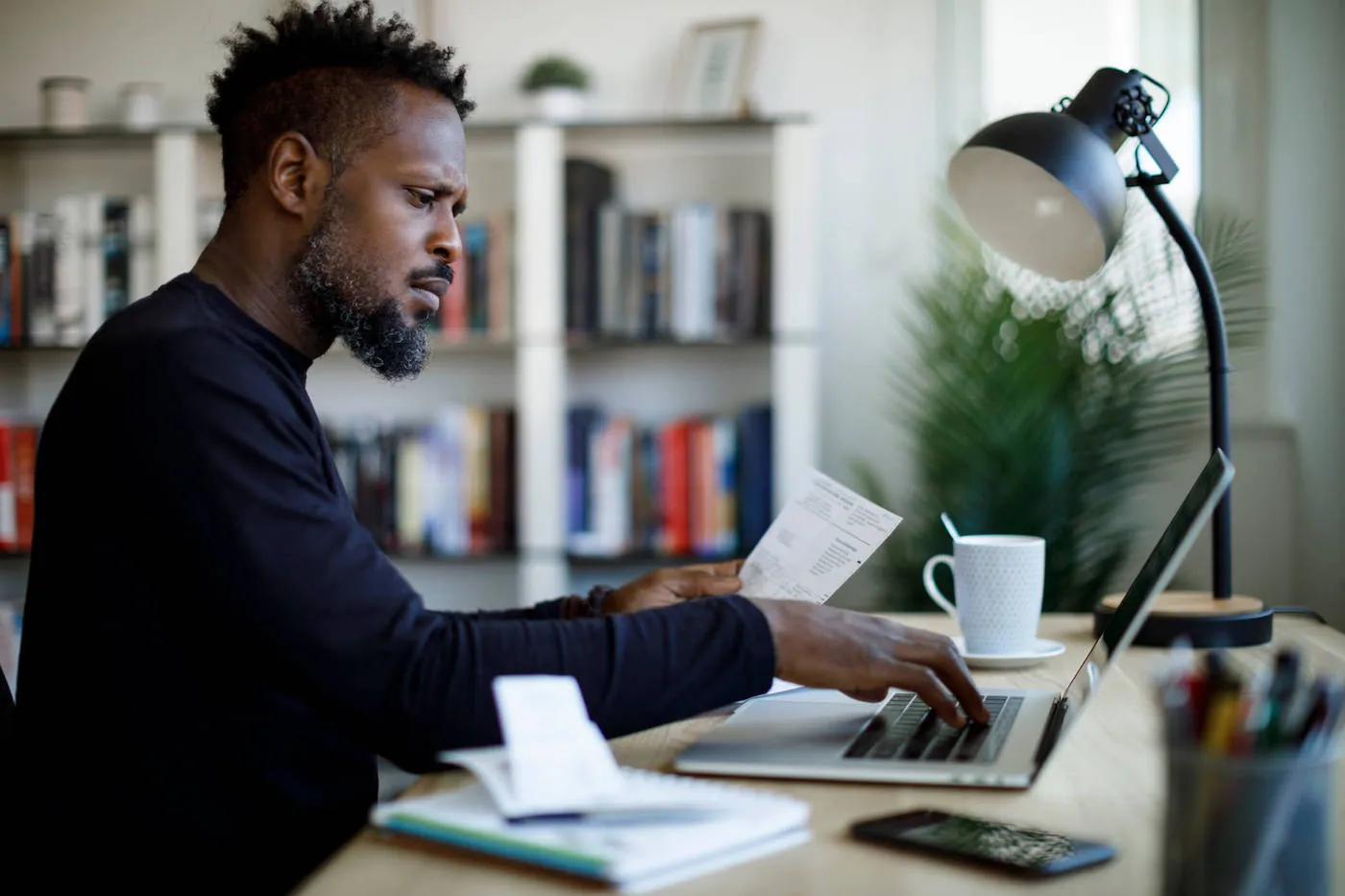 Seated man researching finances on laptop.