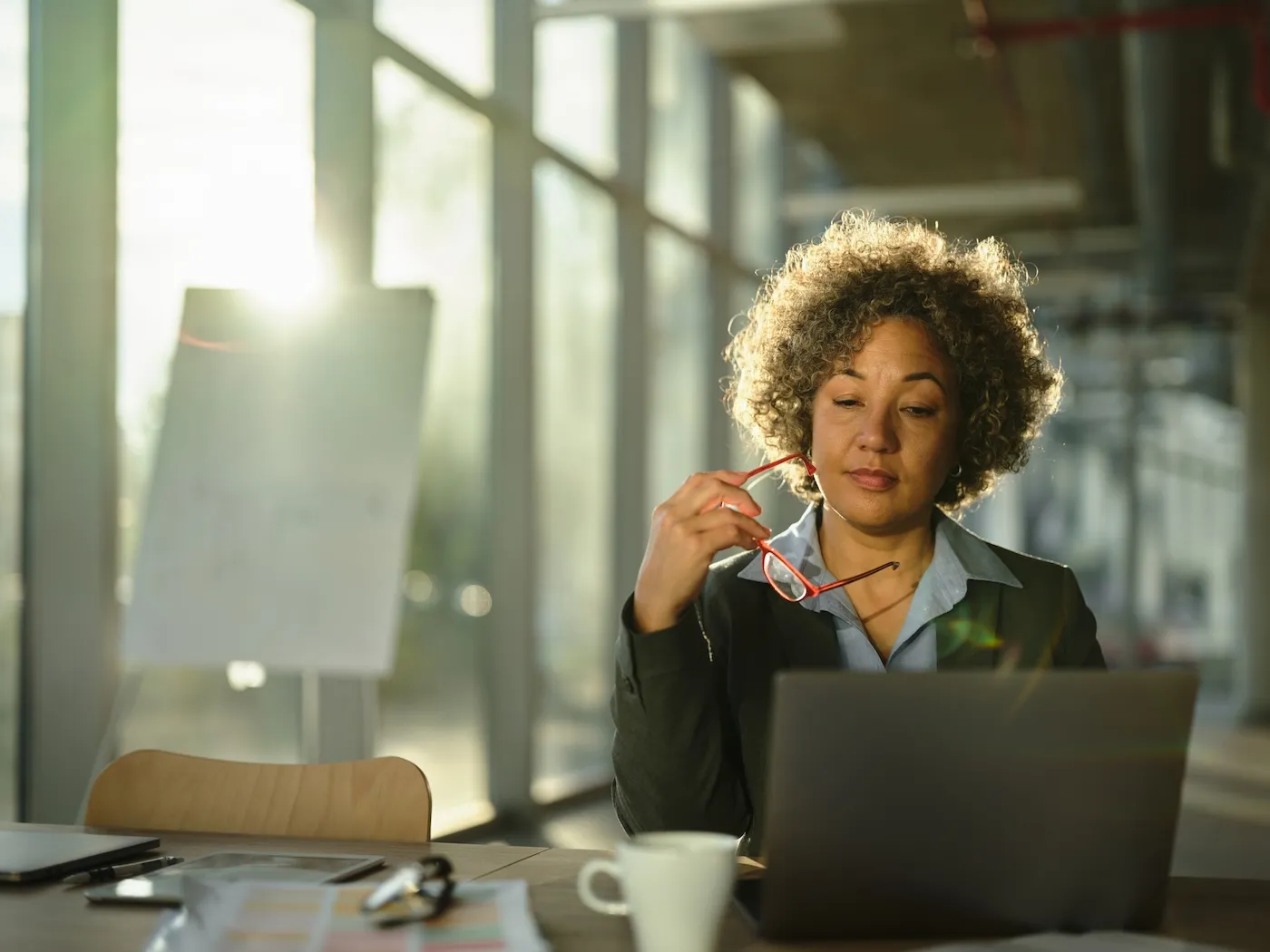 A woman thinking while reading on a computer in the office.