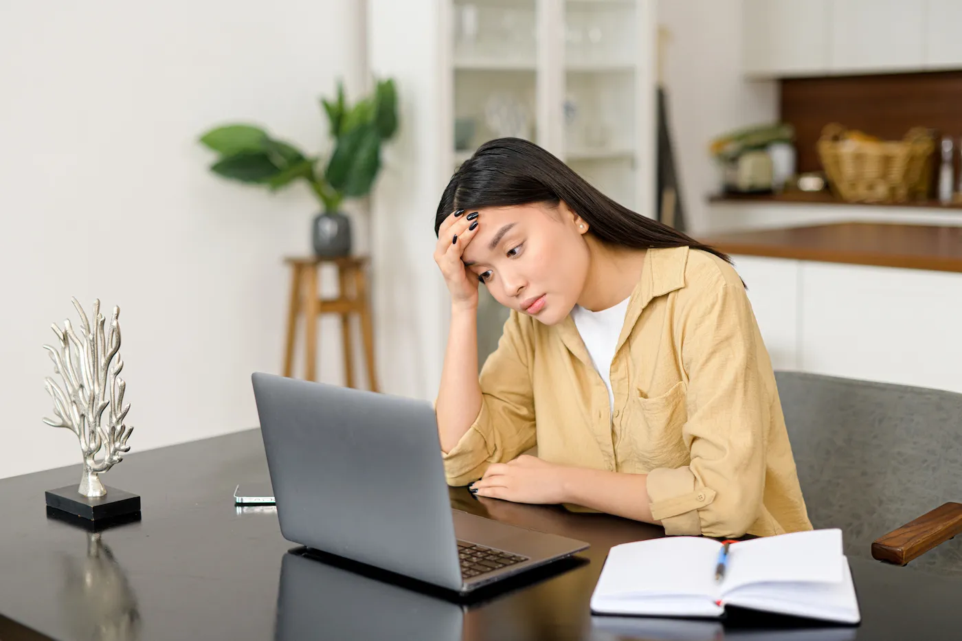 Stressed student looking at her laptop and paying her student loan balance.