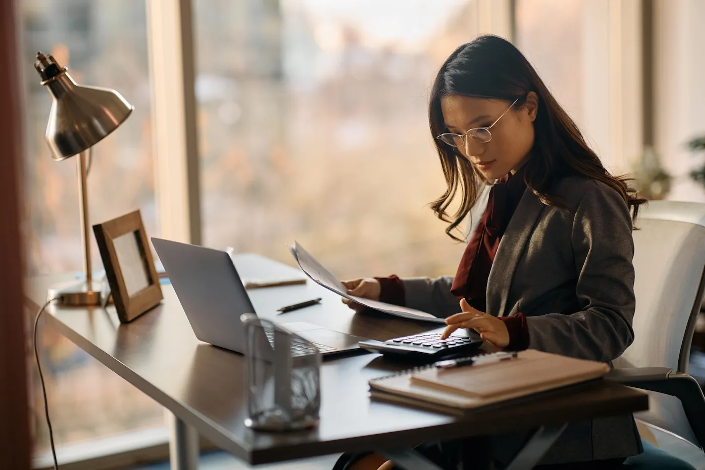 A businesswoman making calculations while going through taxes and working in the office.