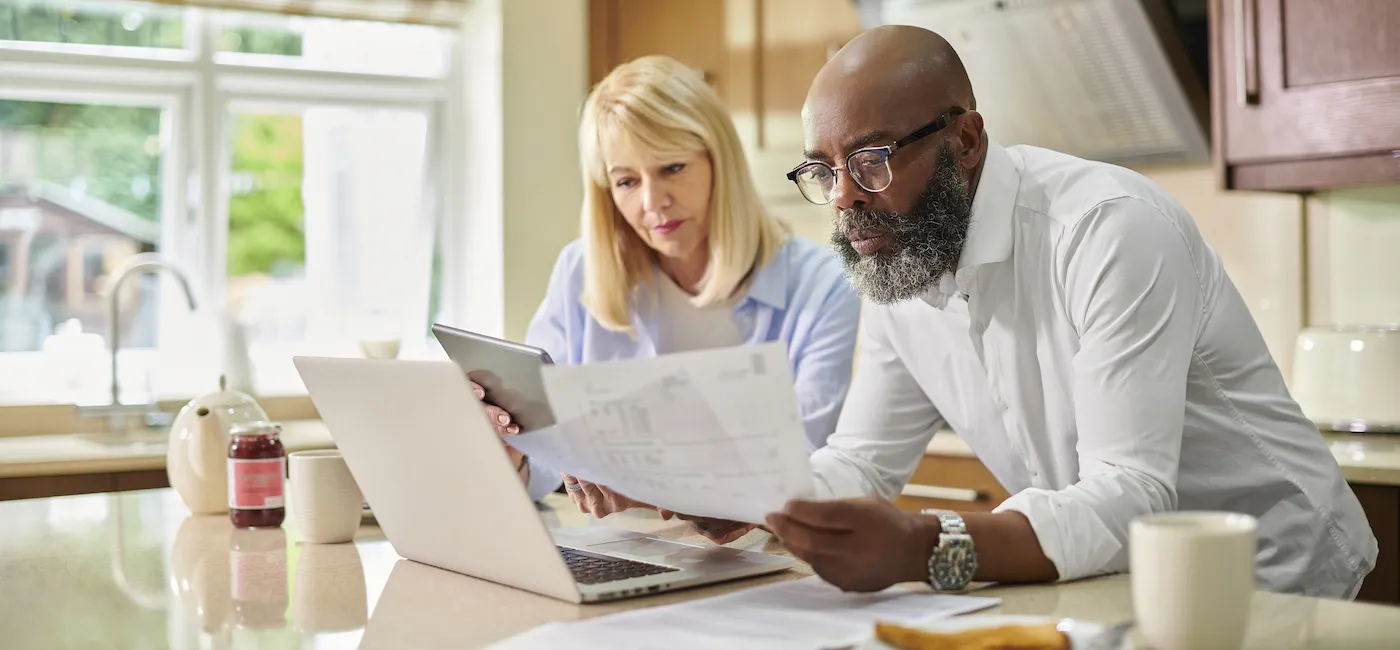 A couple checking their finances online from their kitchen.