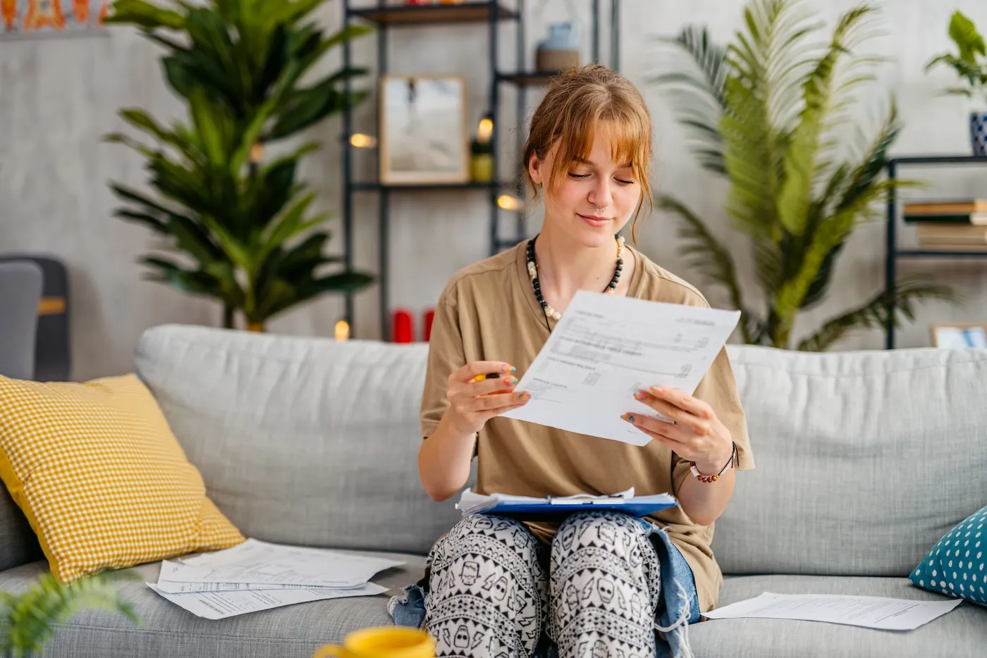 Young woman checking her finances while sitting on the sofa at home.