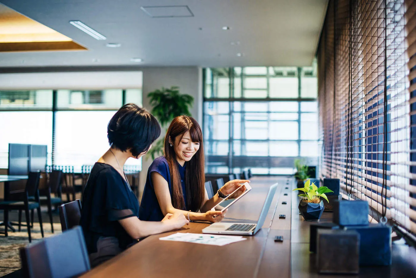 Two women looking at finances on a laptop and a tablet.