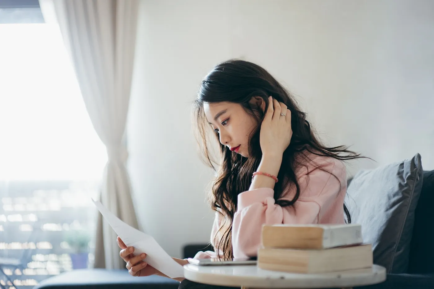 Young woman sitting at home and thinking about how to spend her annual bonus while reading her account statement.