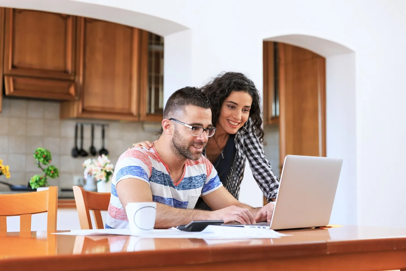 Young woman and man sitting at home and working on home finances, using laptop.