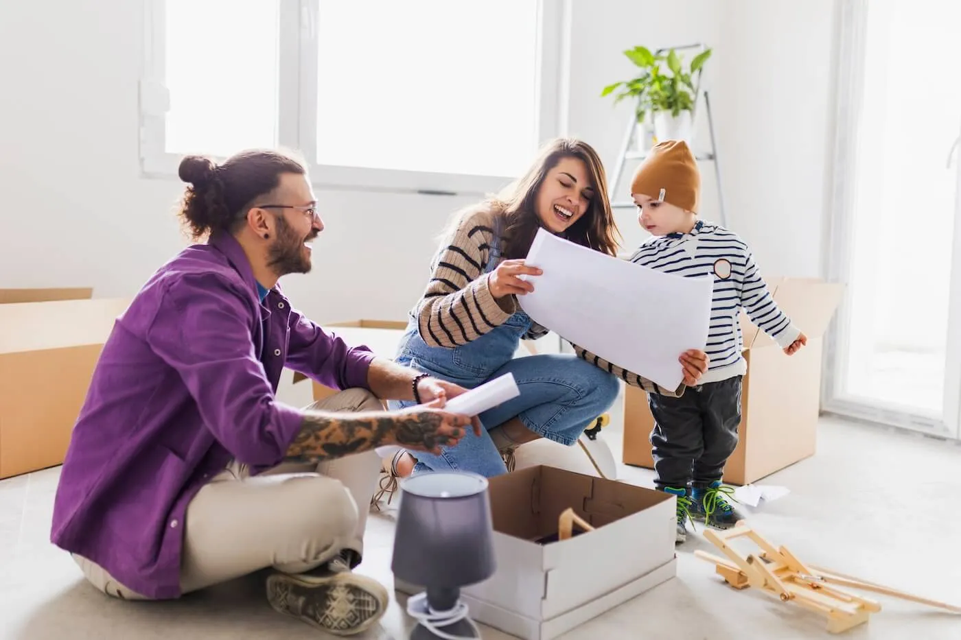 Young family of three sitting on the floor in their new home