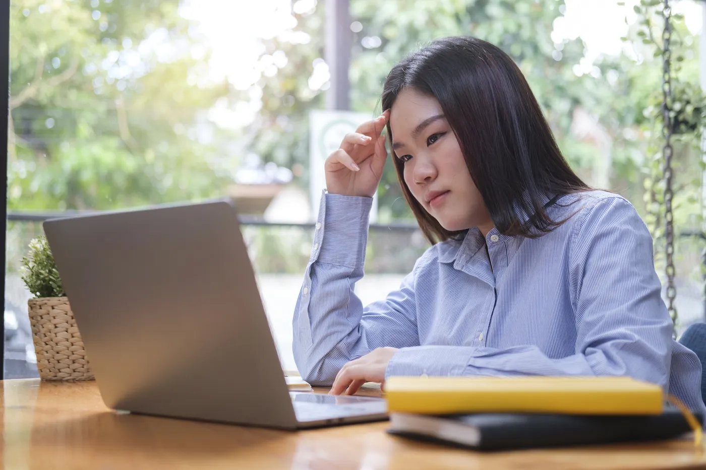 Serious young woman looking at laptop screen and reading her bank statement.