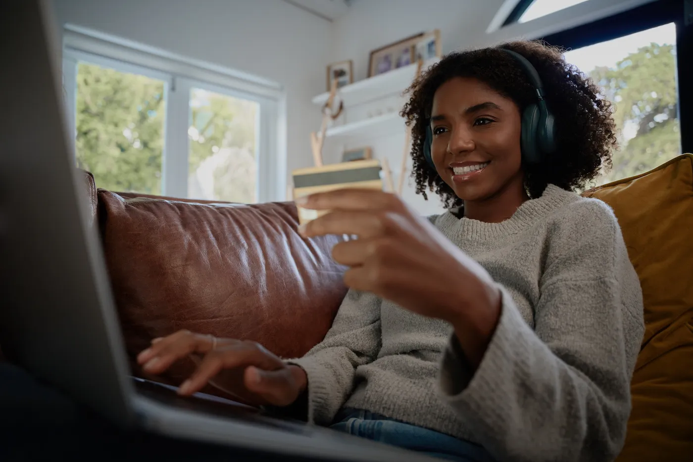 Young woman making online payment using co-branded credit card and laptop