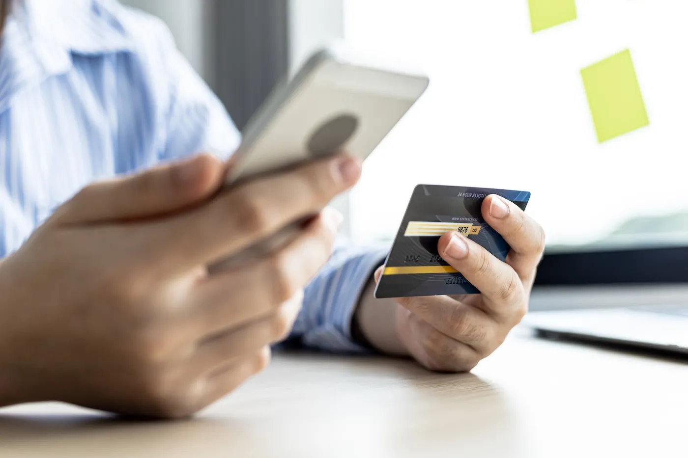 A woman holding a cell phone and credit card.