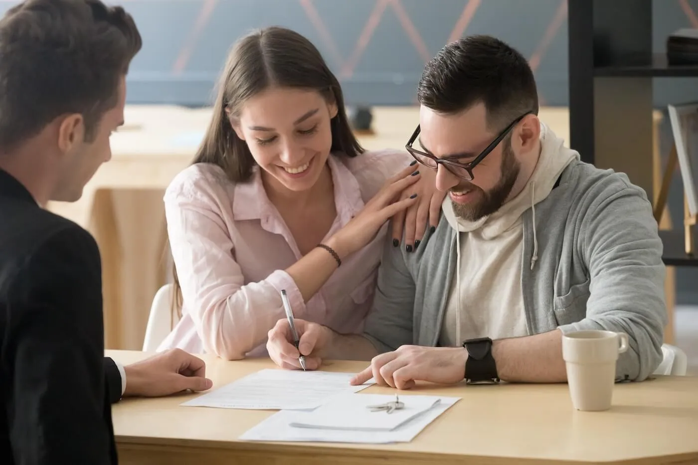 A smiling couple signing the papers in the agent's office