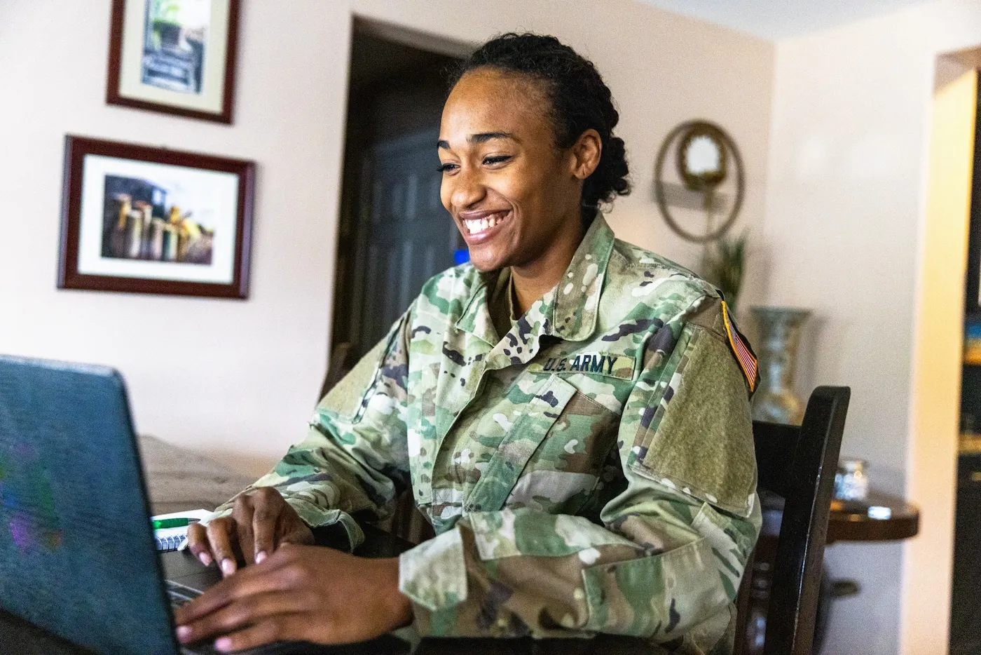 A young US Army Service member working at home on a laptop.