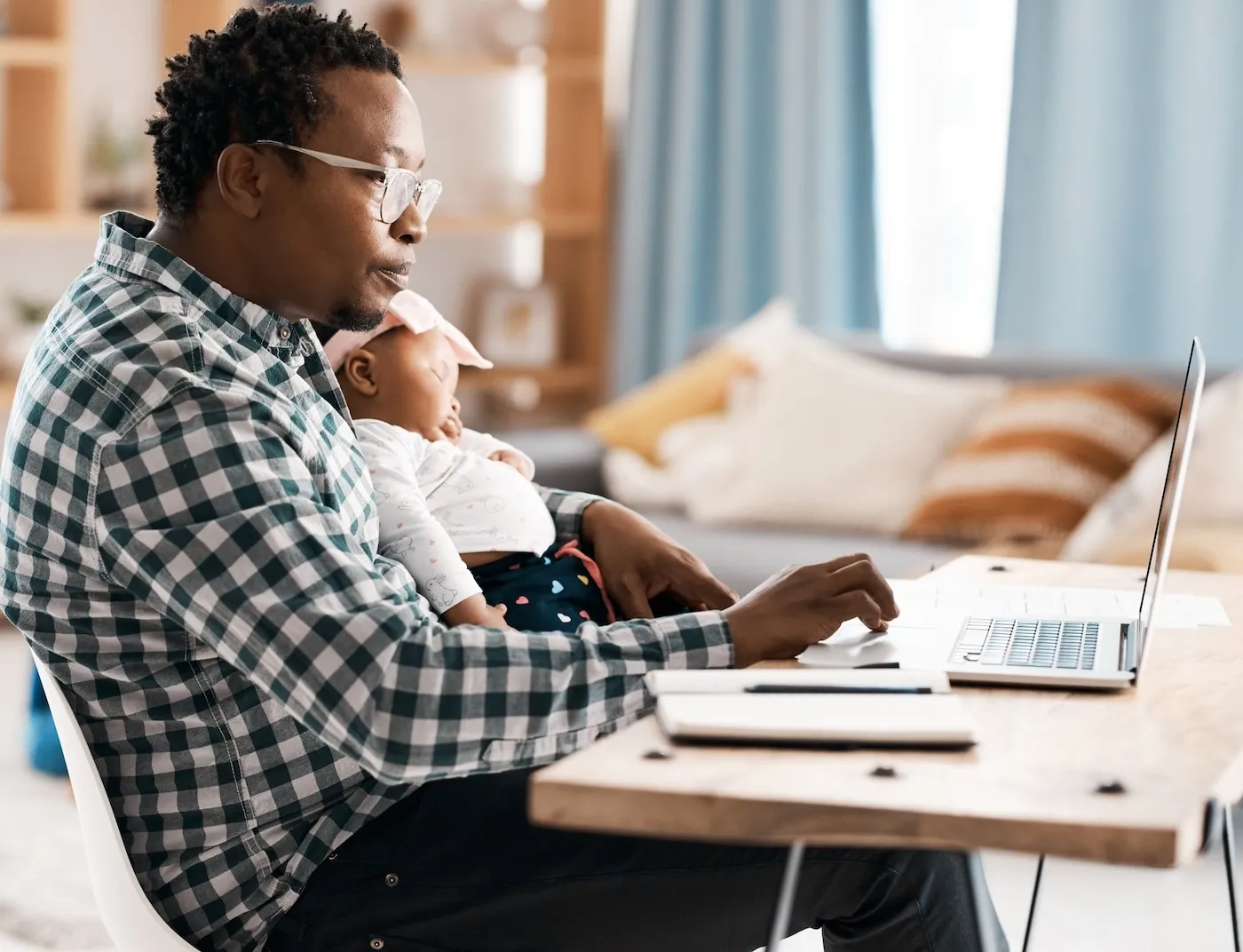 Shot of a man using his laptop while sitting at home with his baby