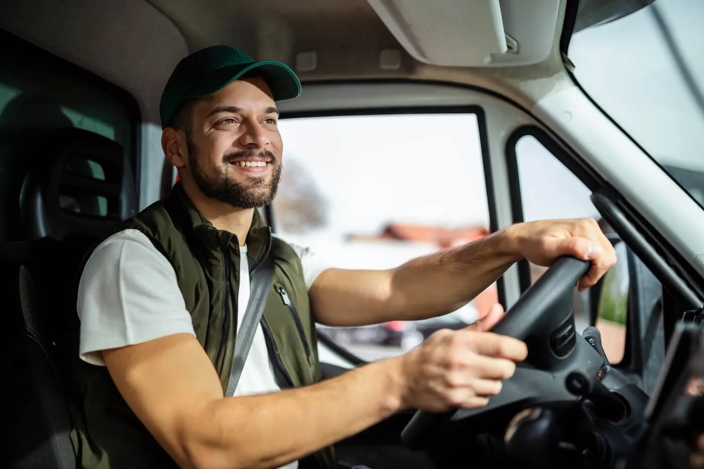 Smiling man in the uniform is driving a commercial vehicle