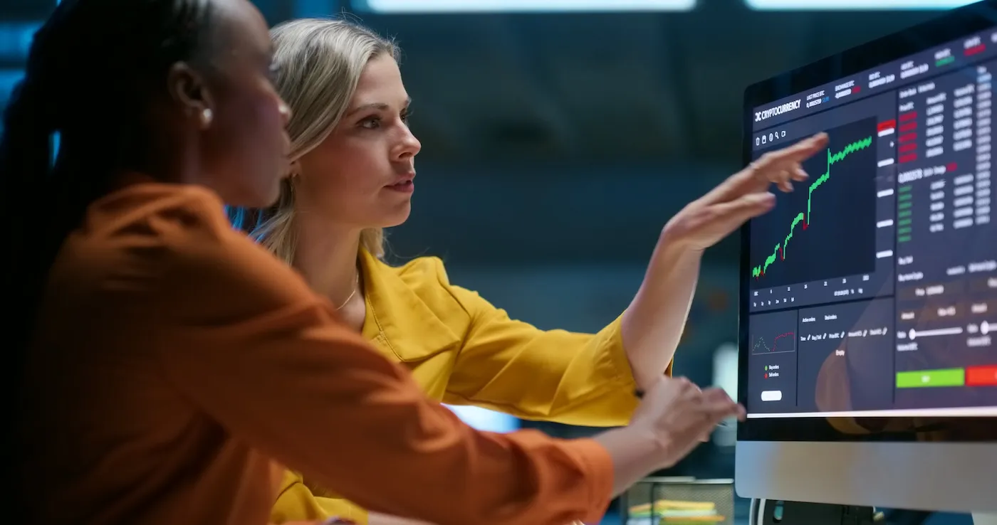 Two women looking at a graph on the computer screen.