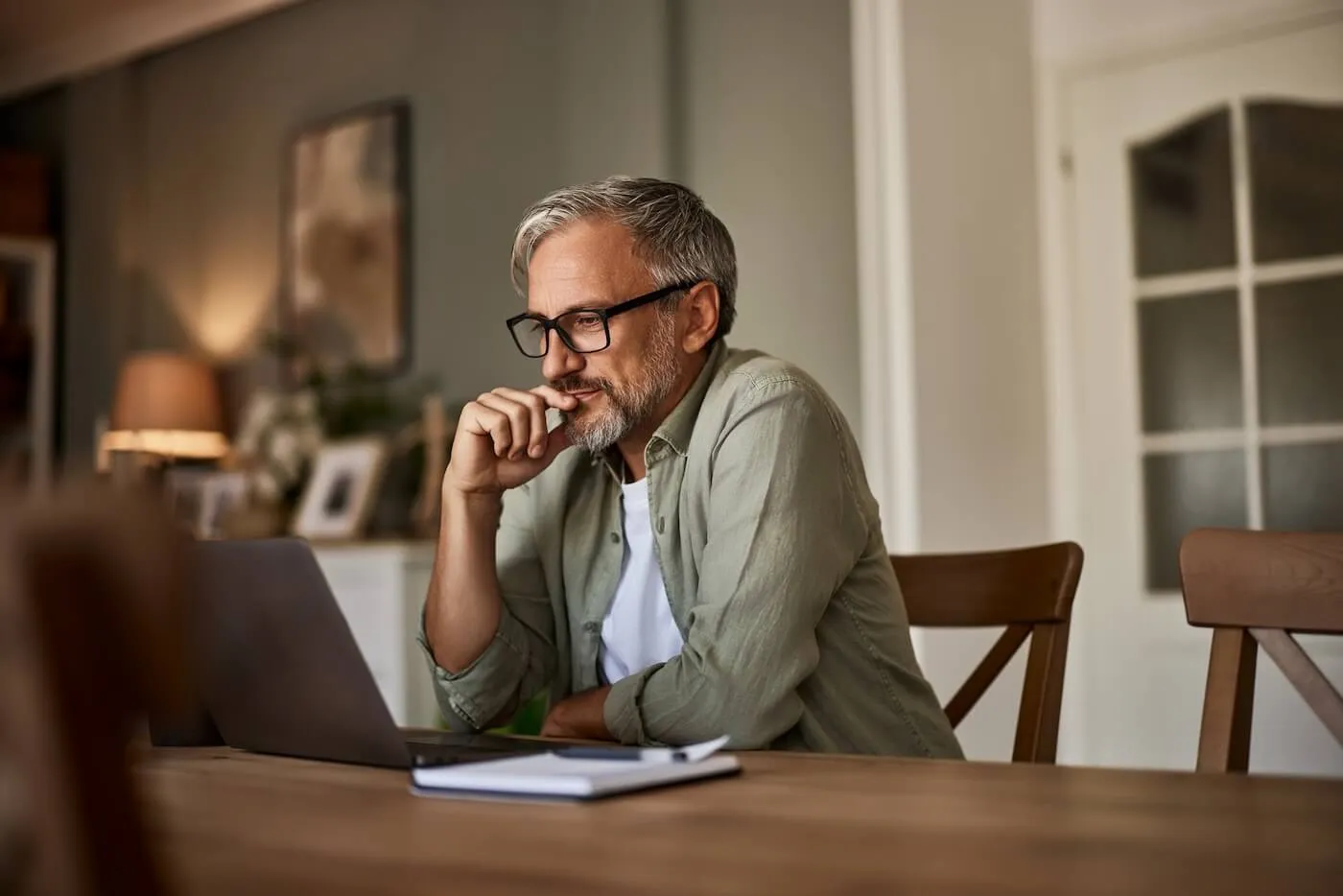 Man working on the laptop with a notepad on the desk