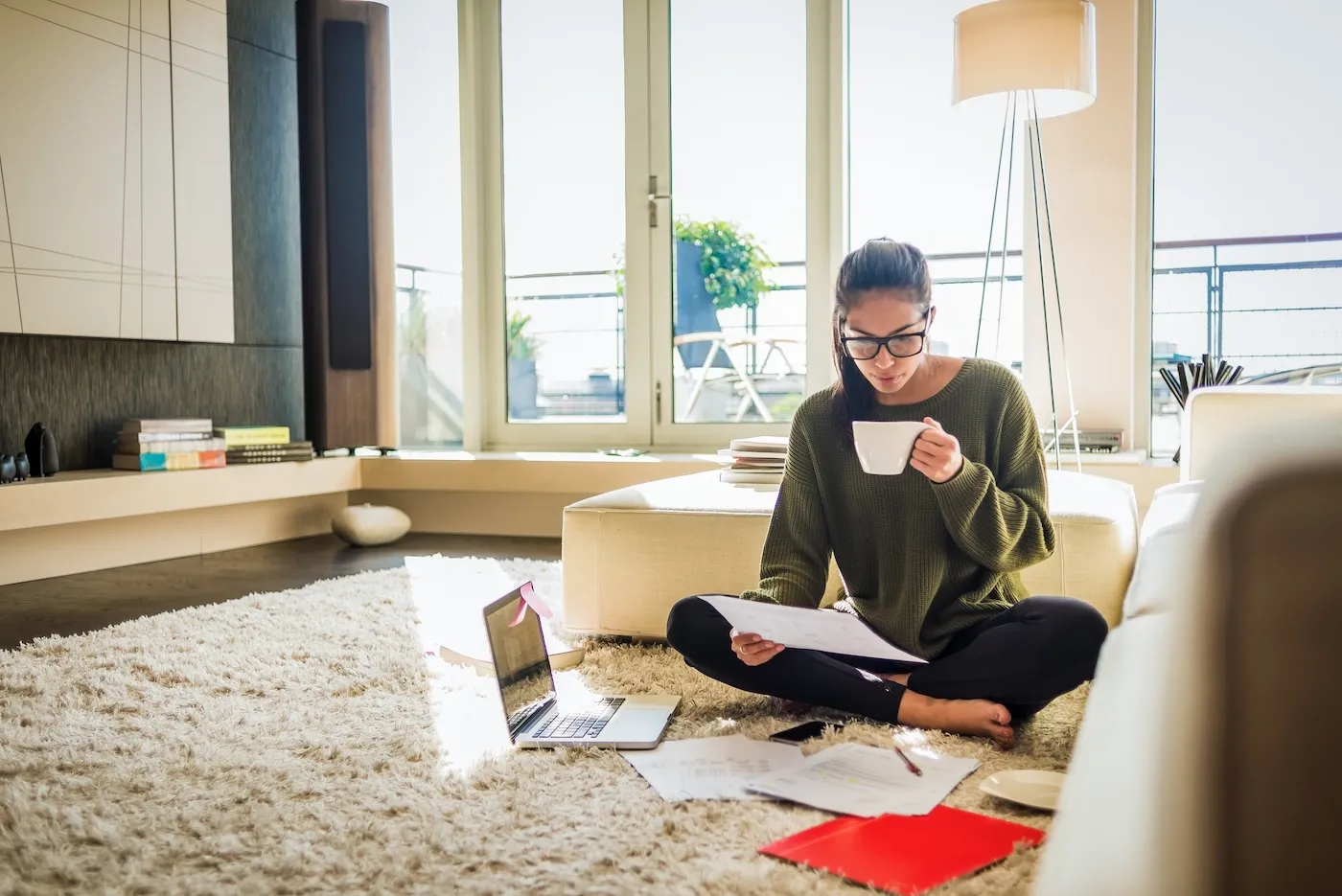 A young woman sitting on the floor of her living room and finding insurance online.