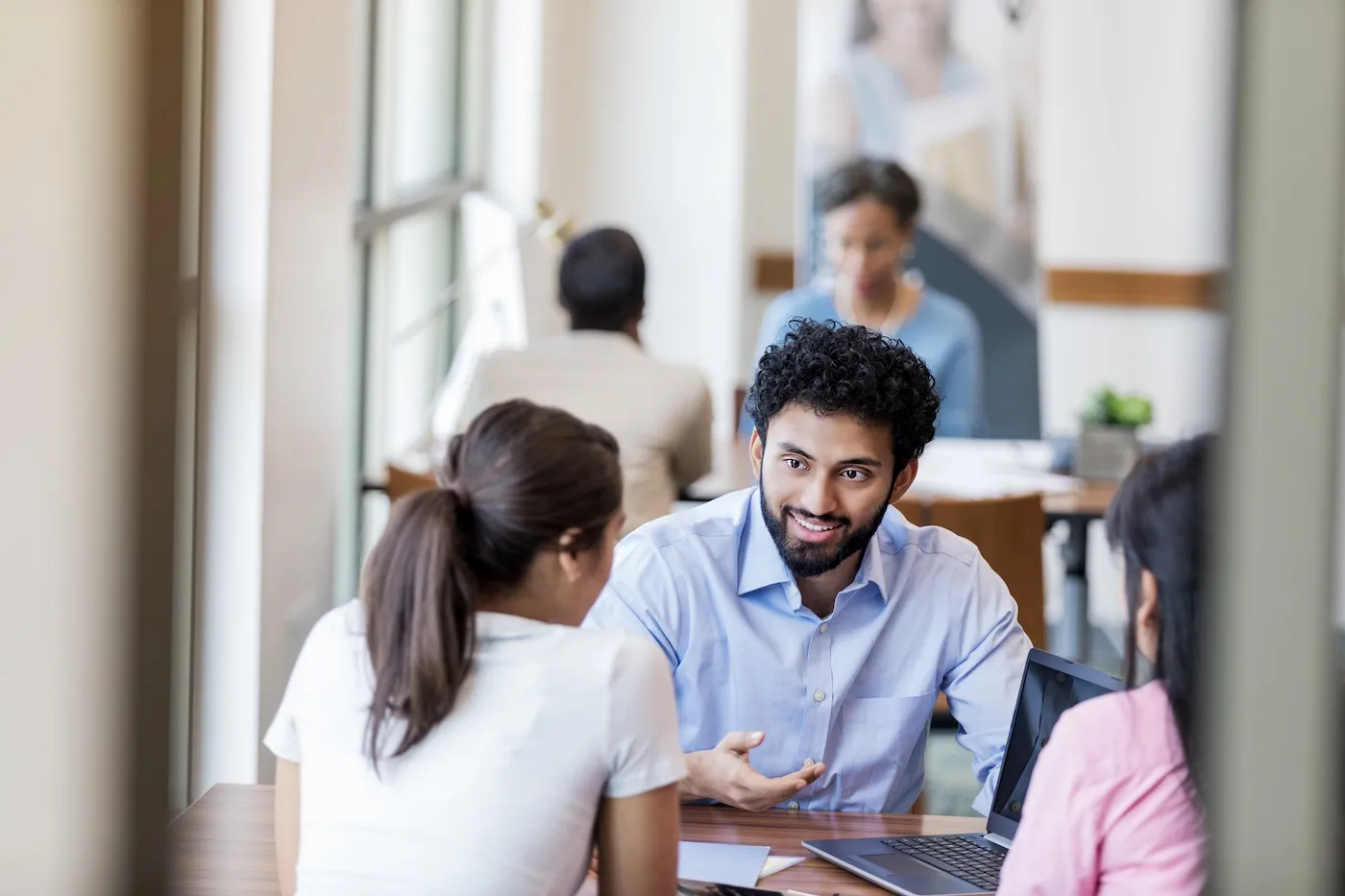 A bank employee discusses loan options with a young woman and her mother.