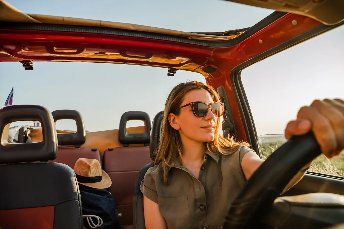 Young woman driving a car and enjoying a beautiful view in nature.