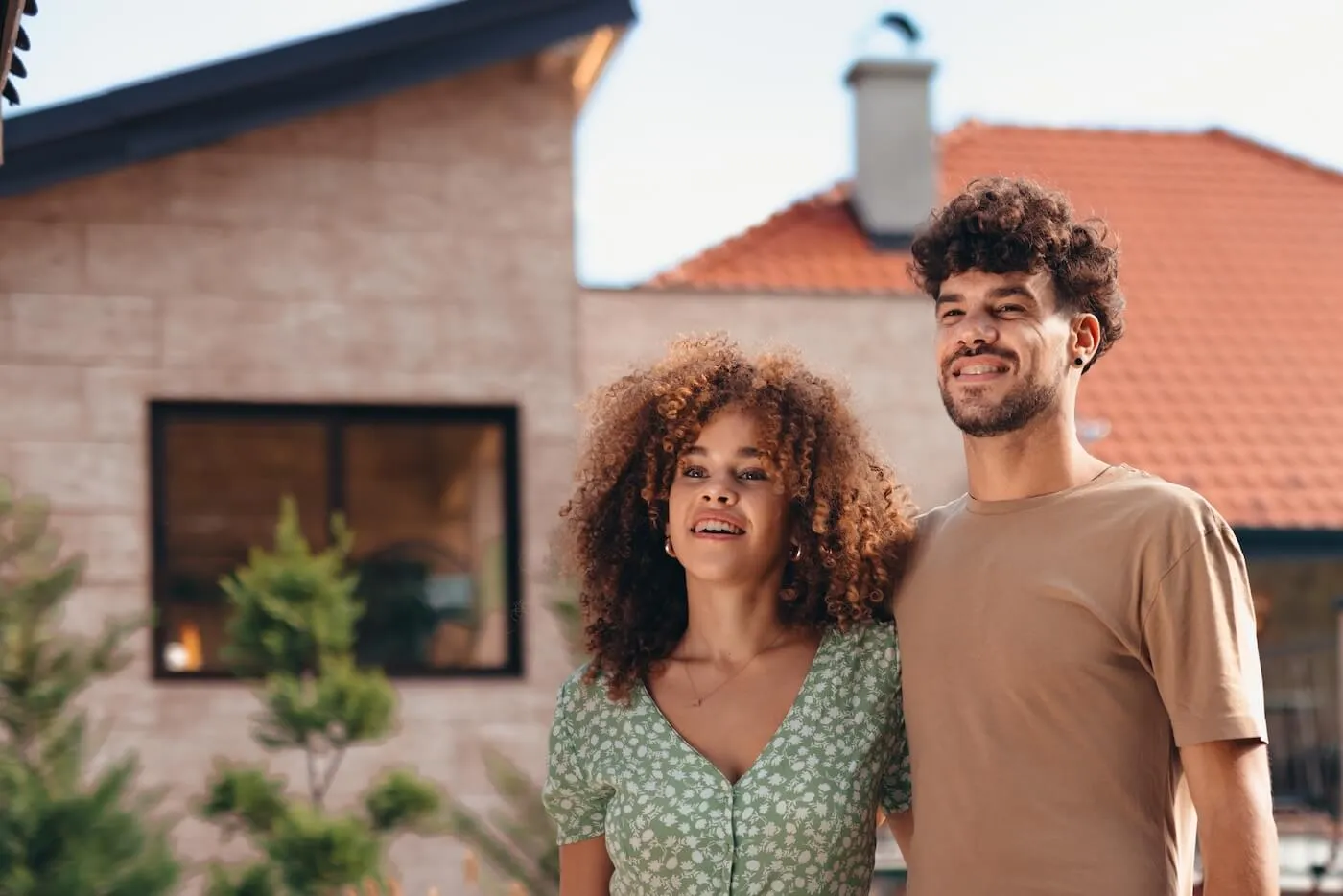 Young couple posing for a photo outside of their house