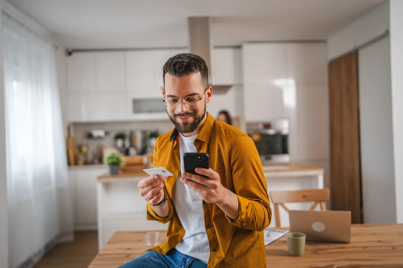 adult man at home shopping online holding a prepaid card.