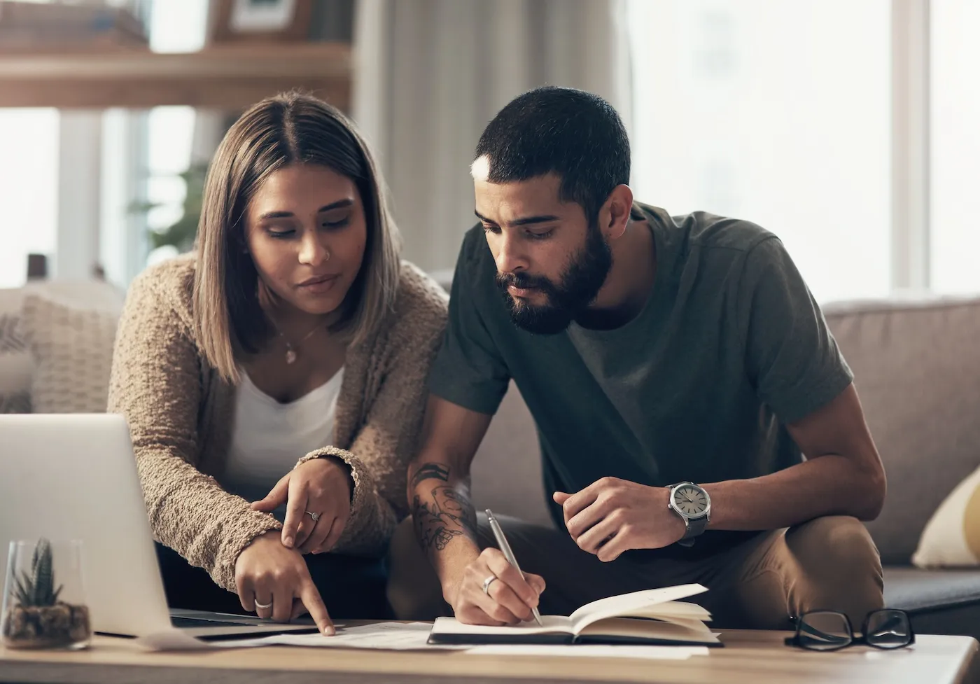 Shot of a young couple using a laptop while going through paperwork at home