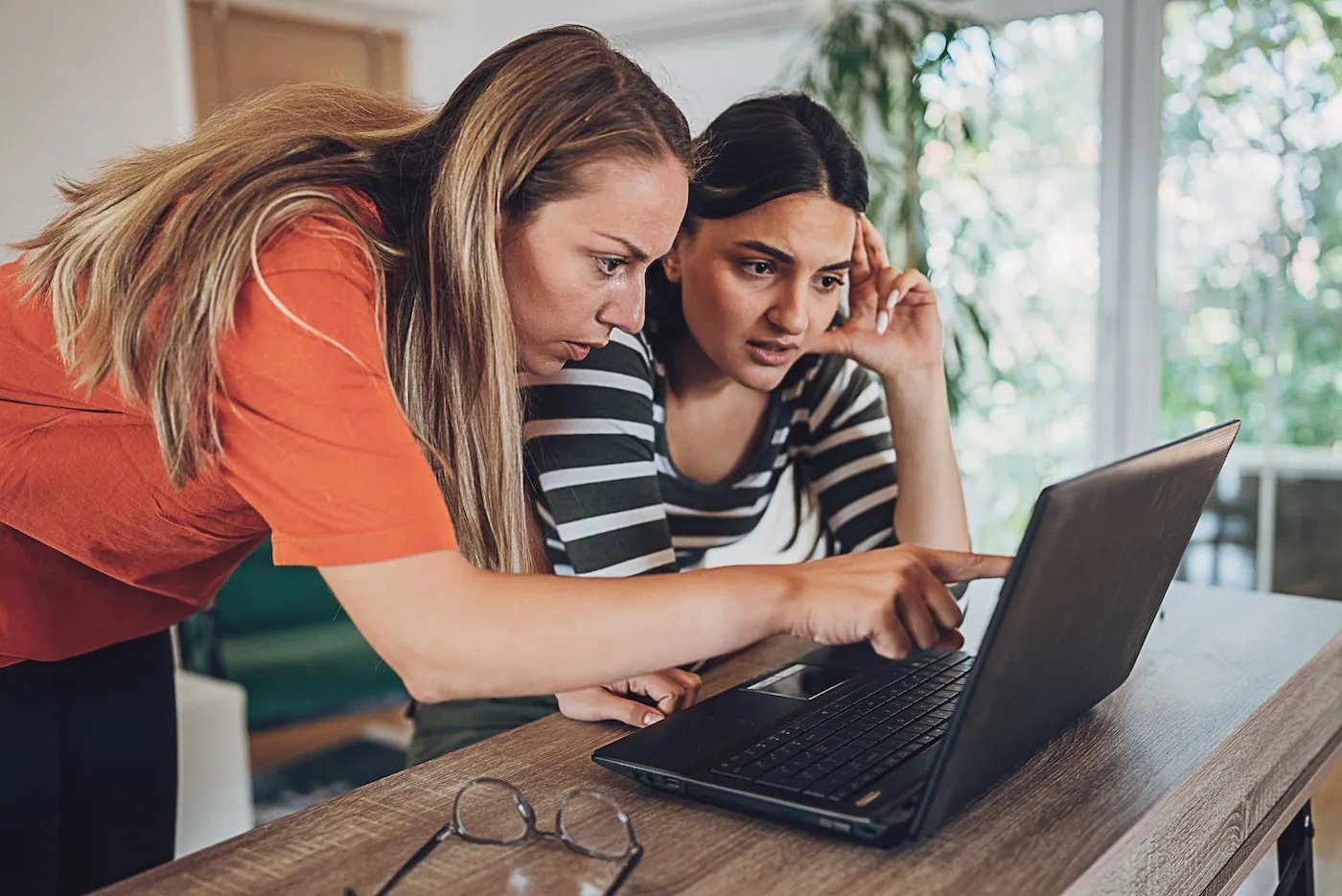 Two young women in distress, looking at a laptop.