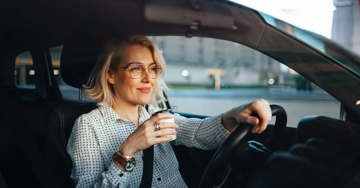 Woman drinking her morning coffee while driving the car