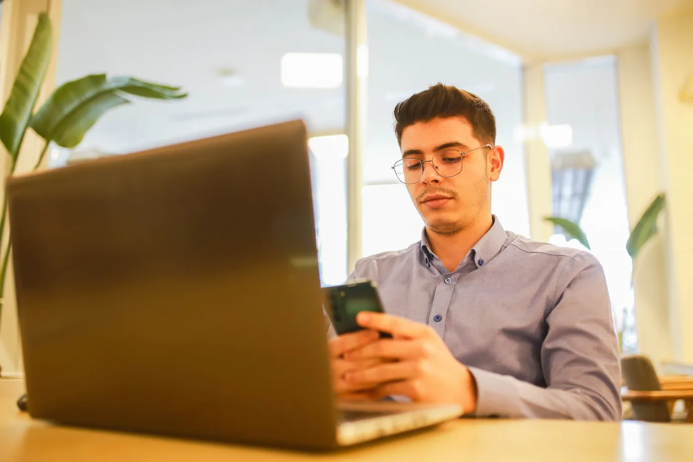 A young man working on his finances with laptop in a cafe.