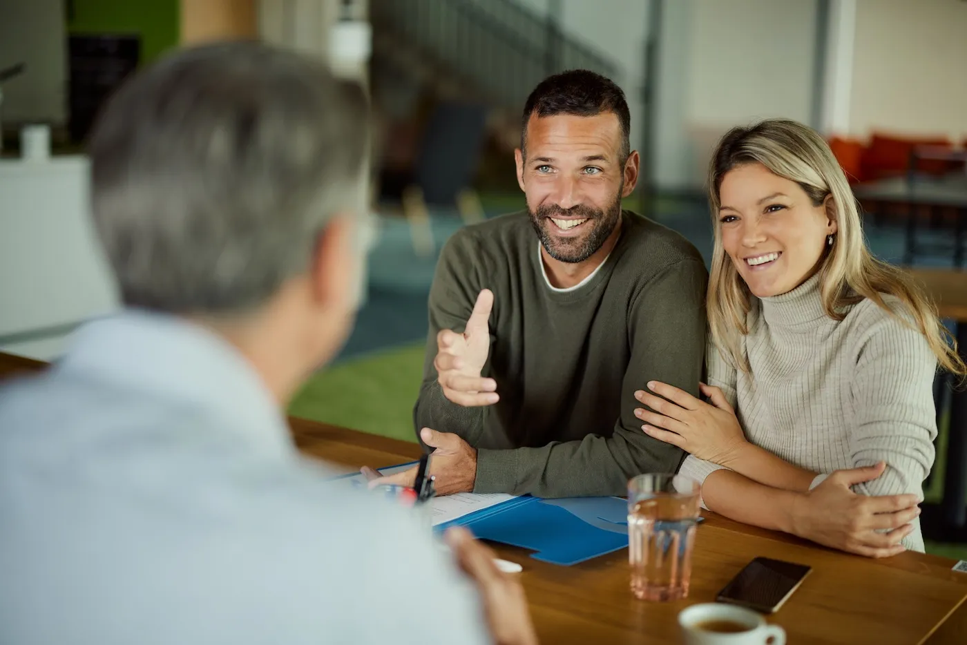 Young happy couple communicating with their agent during a meeting in the office.