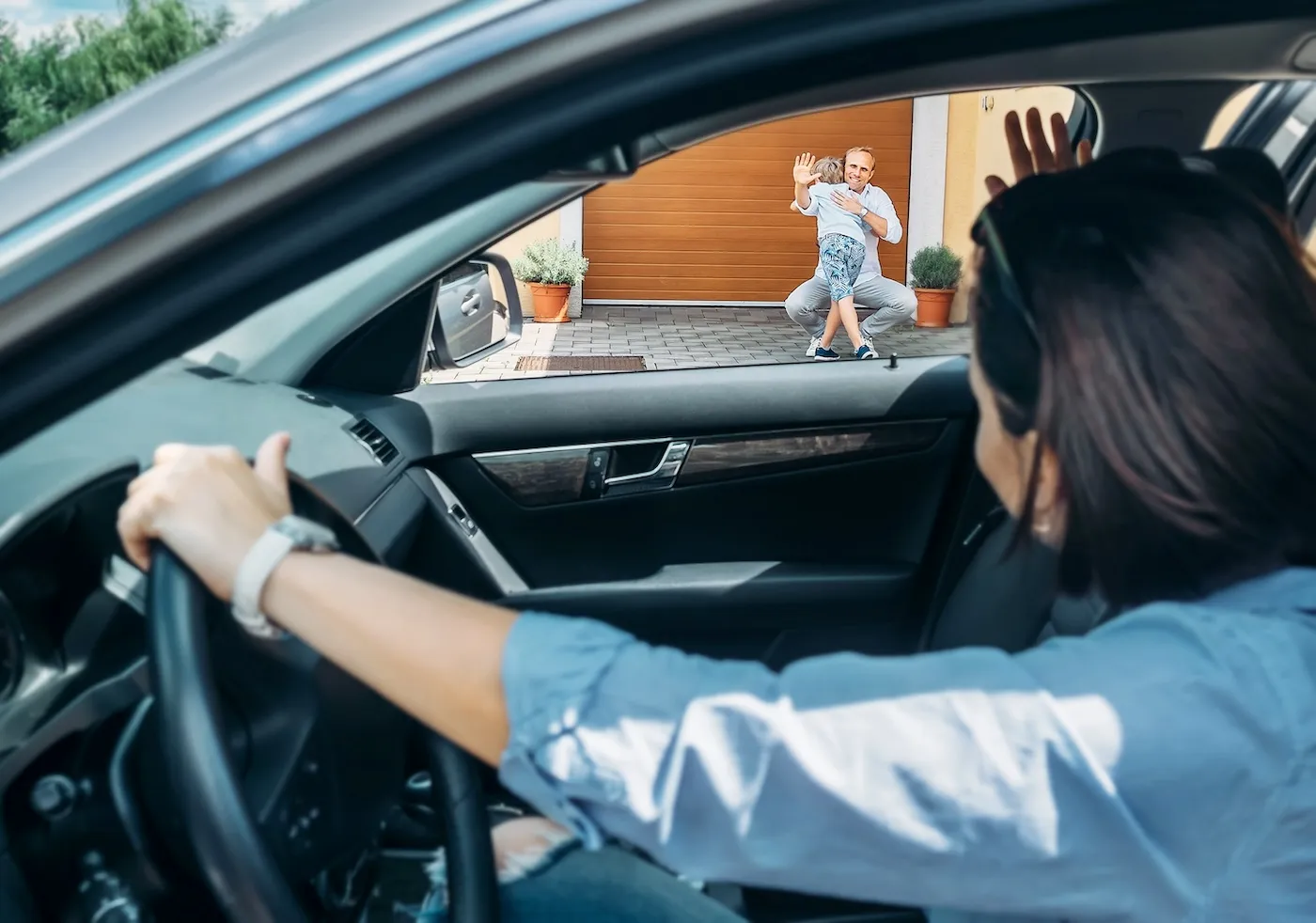 A woman in her car dropping her child off to her ex husband.