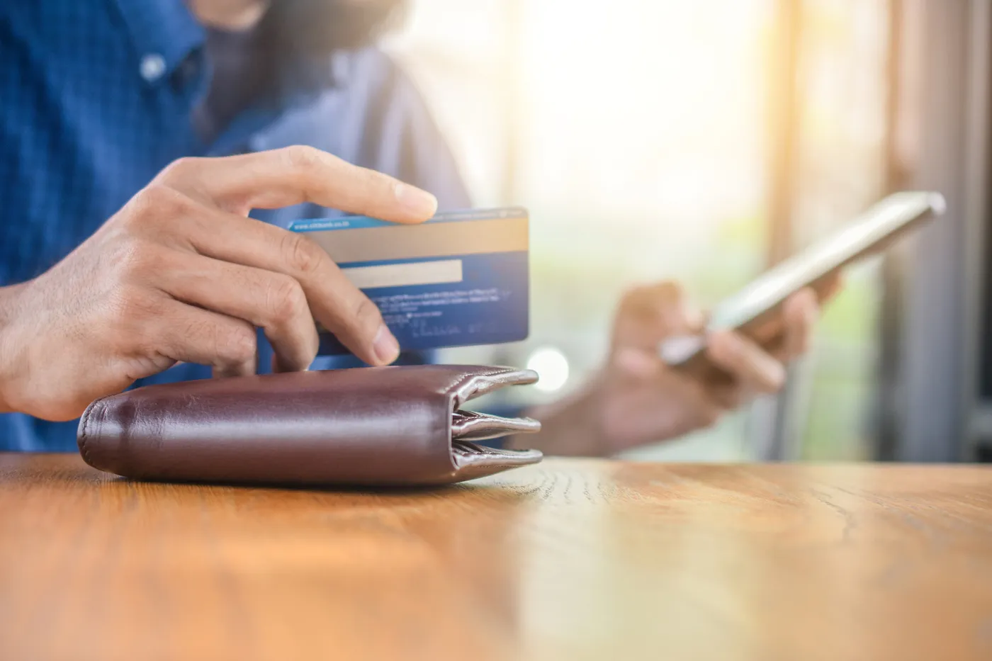 A person holding a debit card and a mobile phone