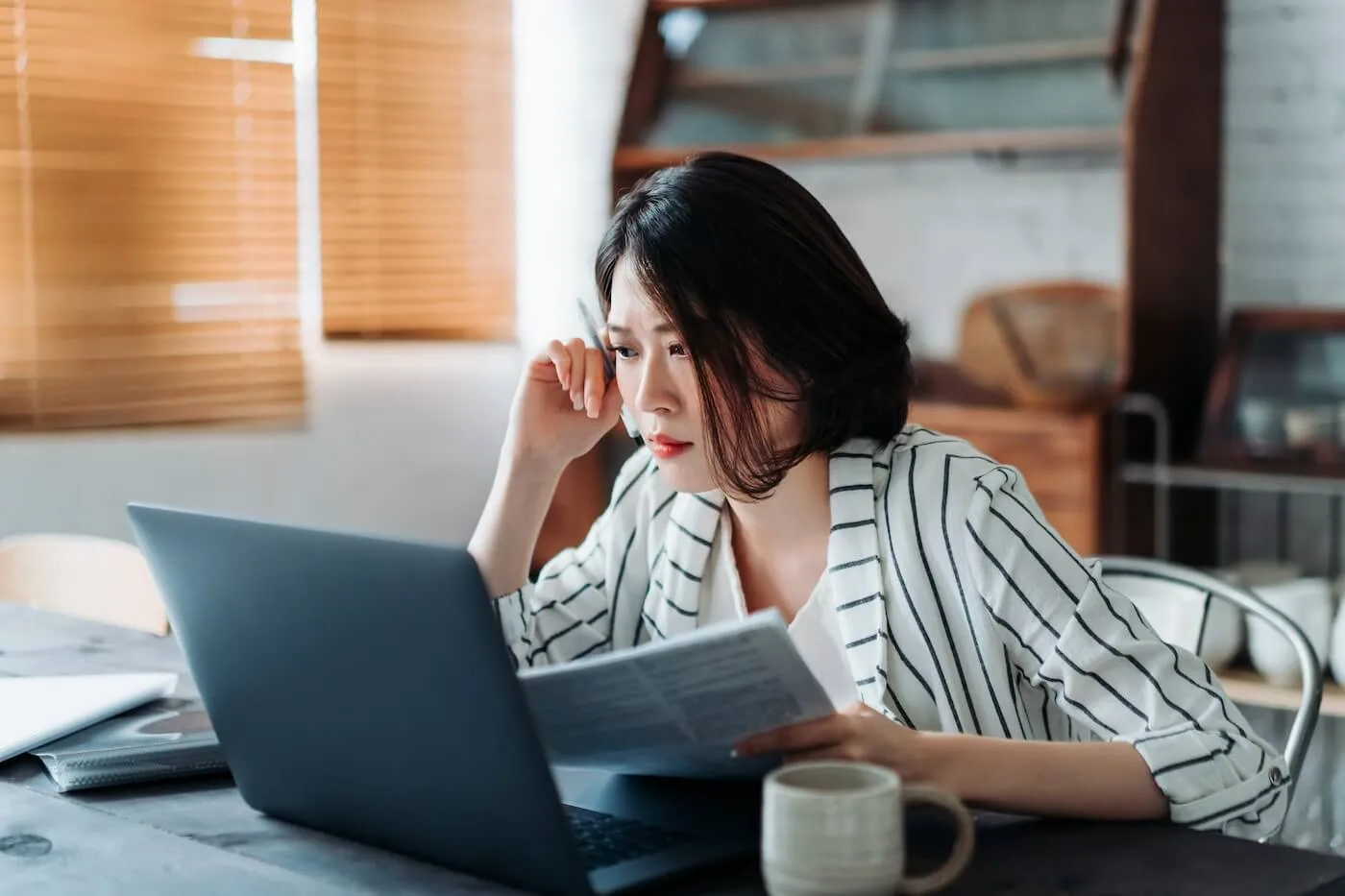 A concerned woman looking at the monitor while holding the papers