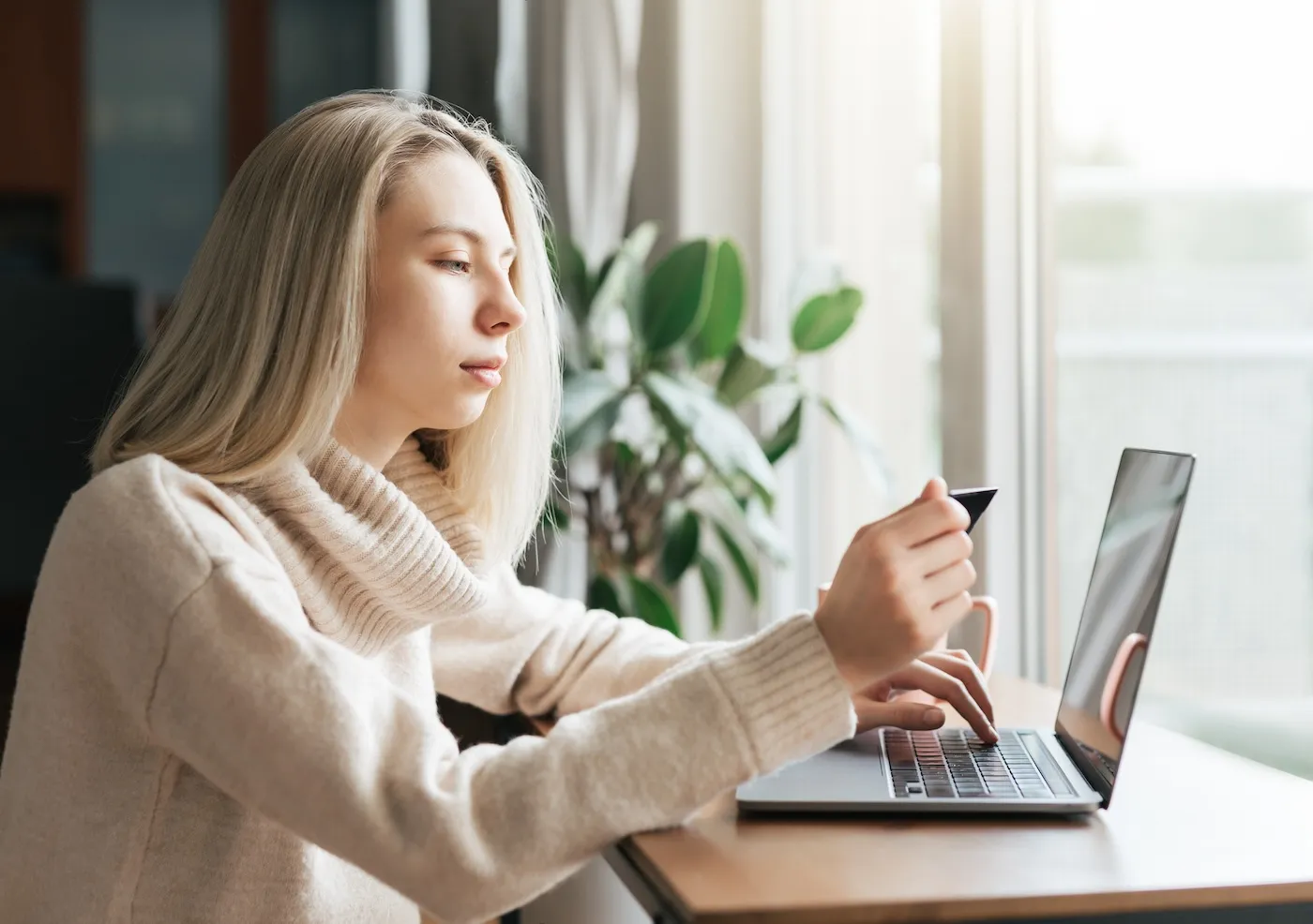 Young woman holding credit card and using laptop computer.