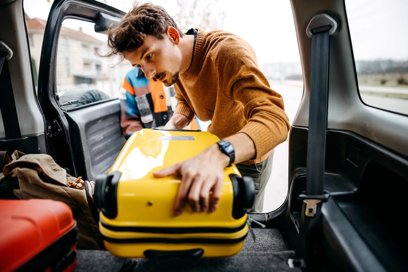 Young couple packing and loading luggage into car trunk to move houses.