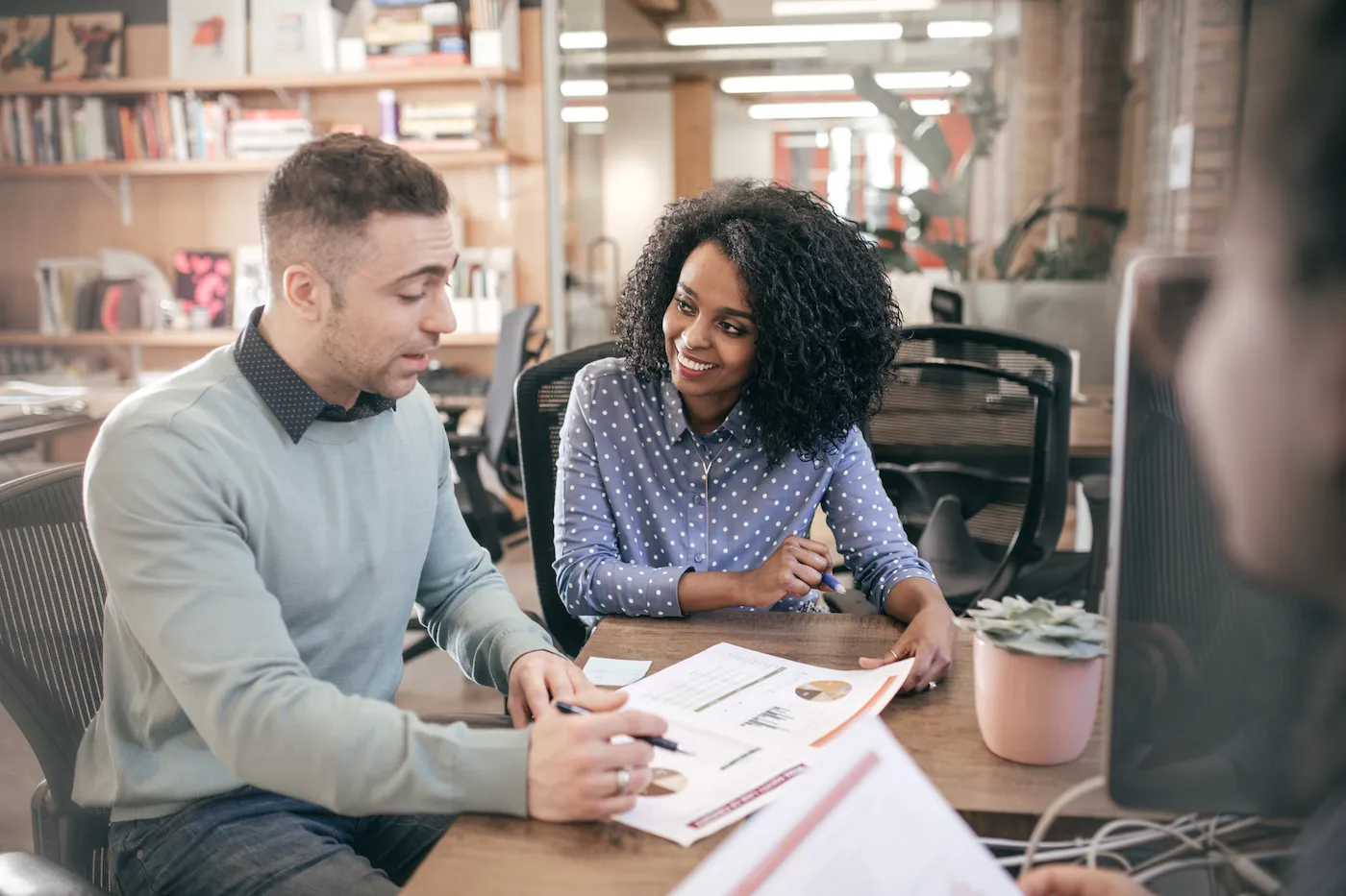 A woman and man reviewing investment strategy in a library.