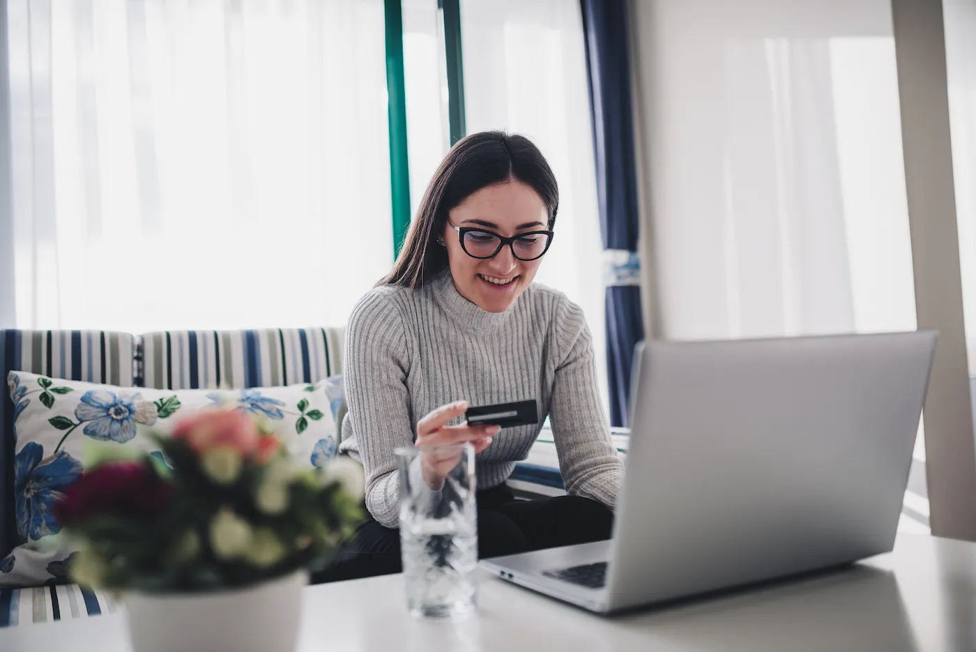 Young woman at home using laptop and credit card, avoiding common mistakes.