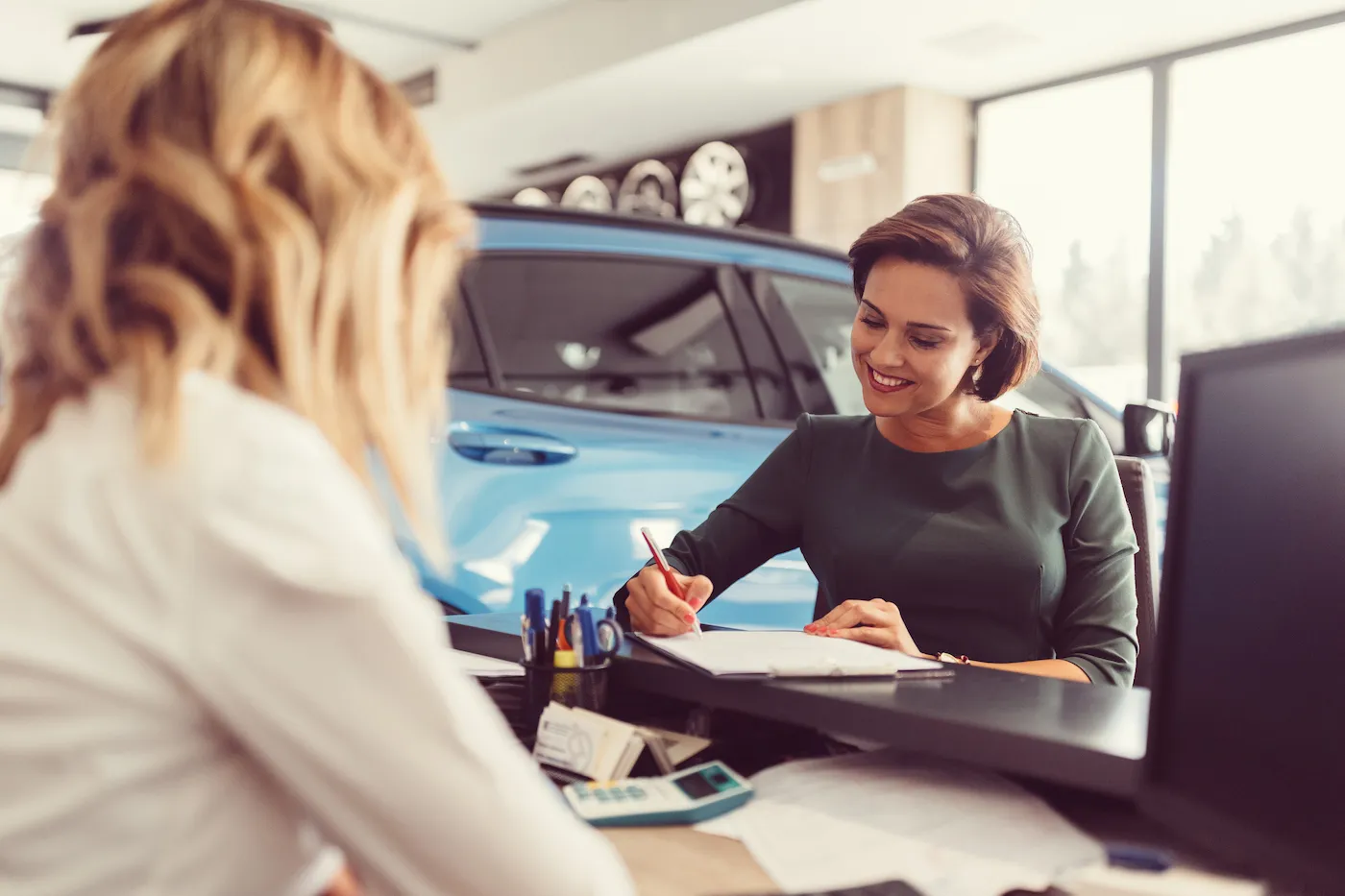 Car dealer sales car to the customer, a woman leasing a car.