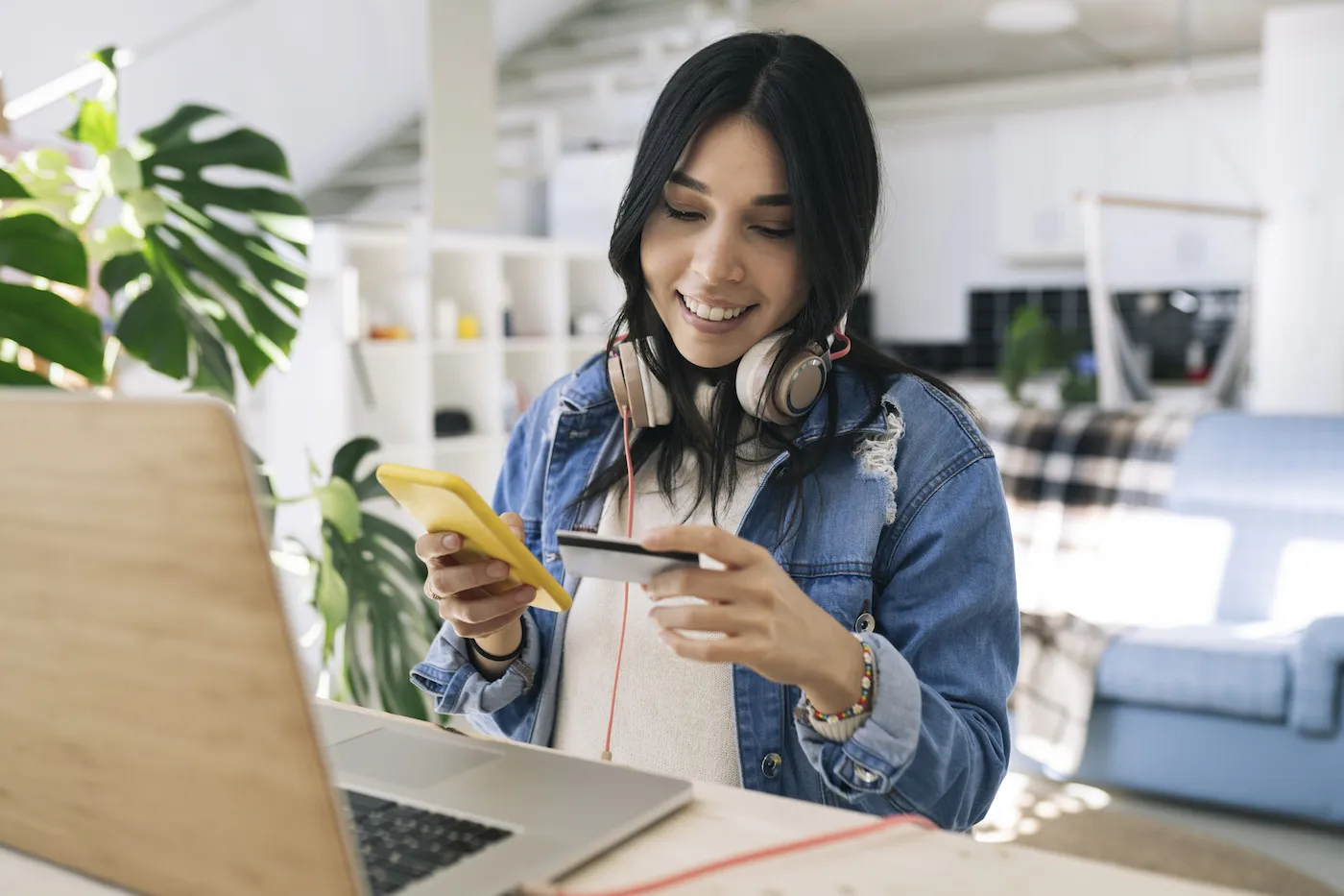 A woman using her phone and looking at a credit card