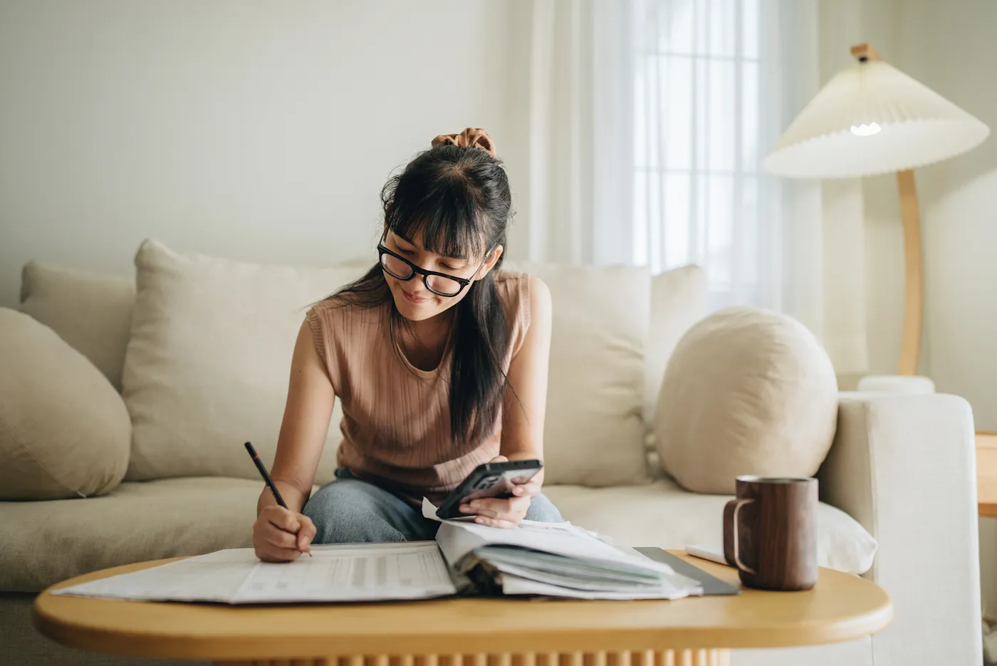 A woman sits at her living room paying her bills on time