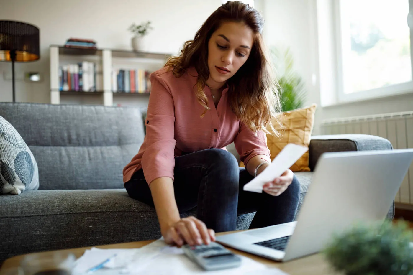 Woman seating on sofa going over financial accounts.