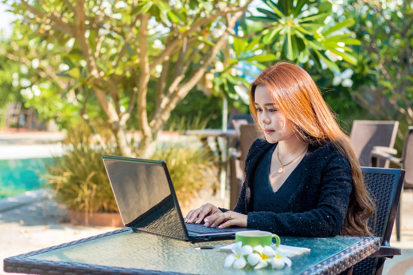 Woman sitting outside checking her savings account on her laptop