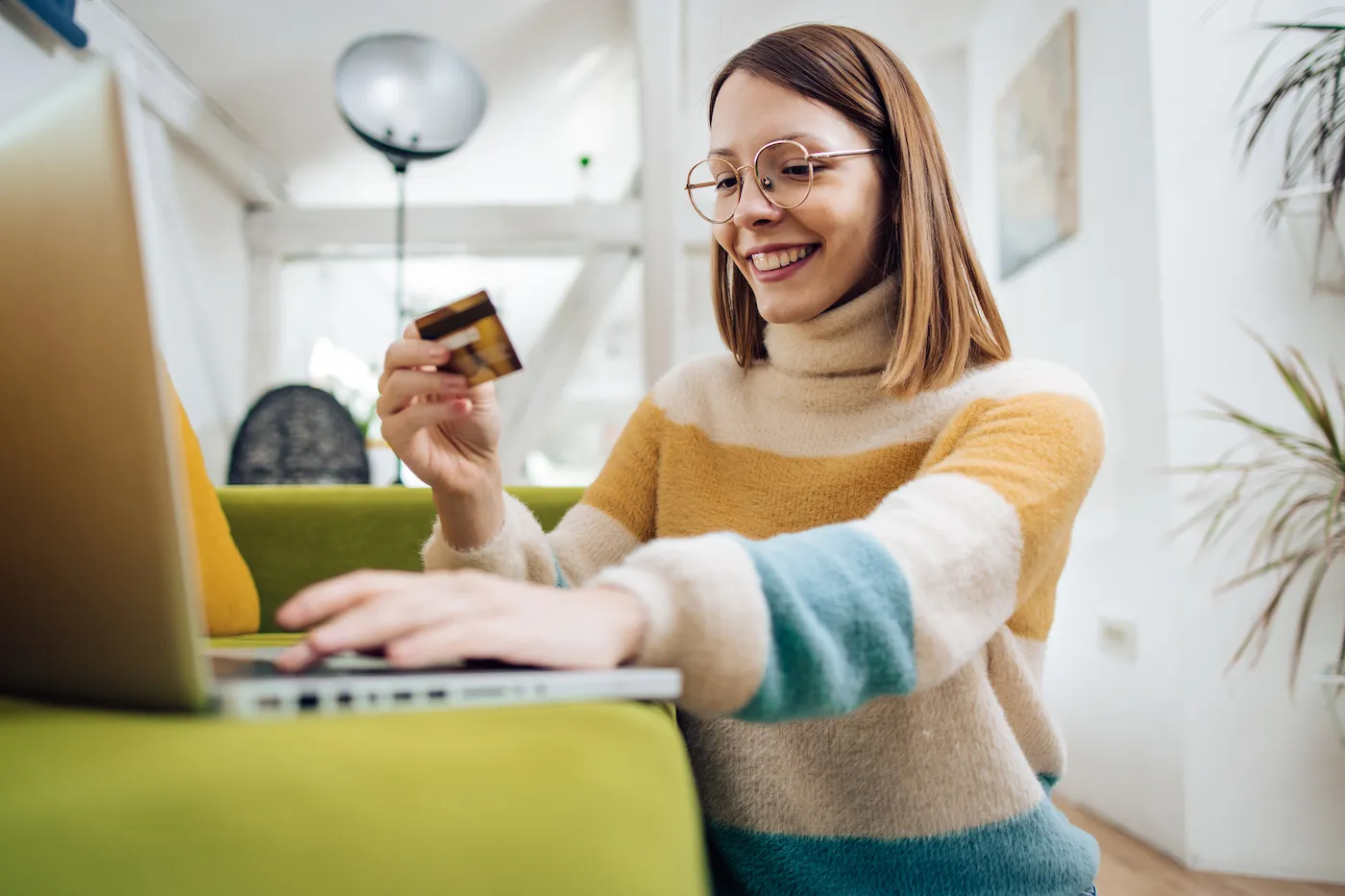 woman using her debit card to use her checking account, sitting at her laptop