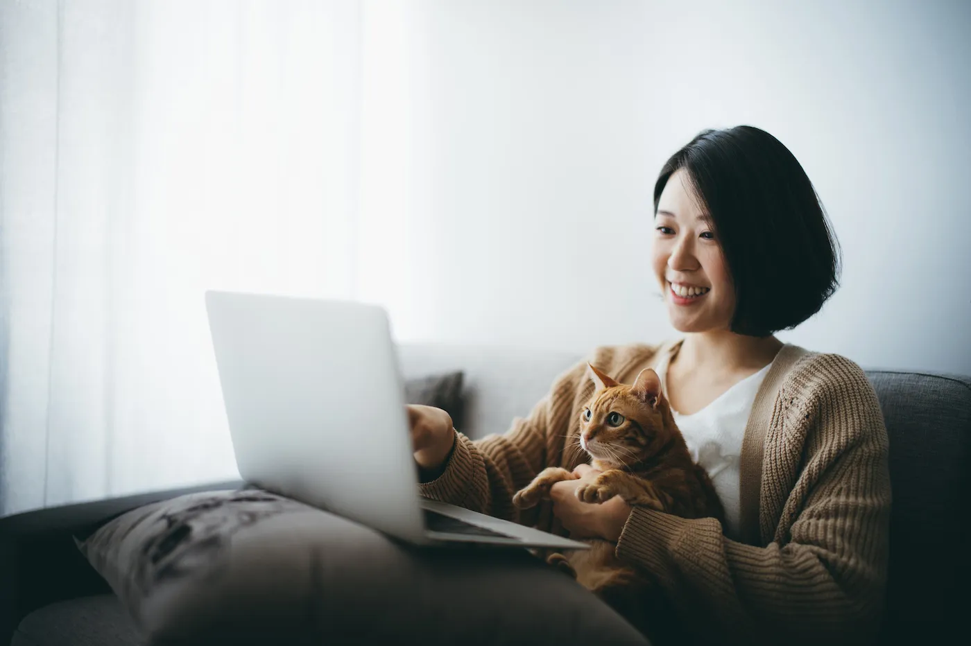 Cheerful woman sitting on the couch with her cat at home, withdrawing from a CD.