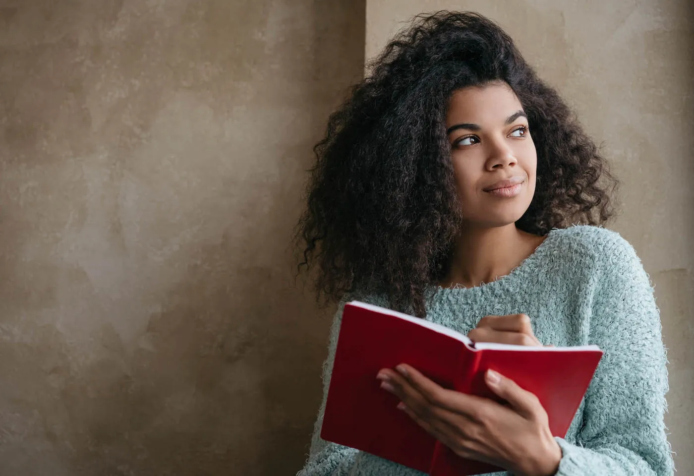 Woman writing in red notebook.