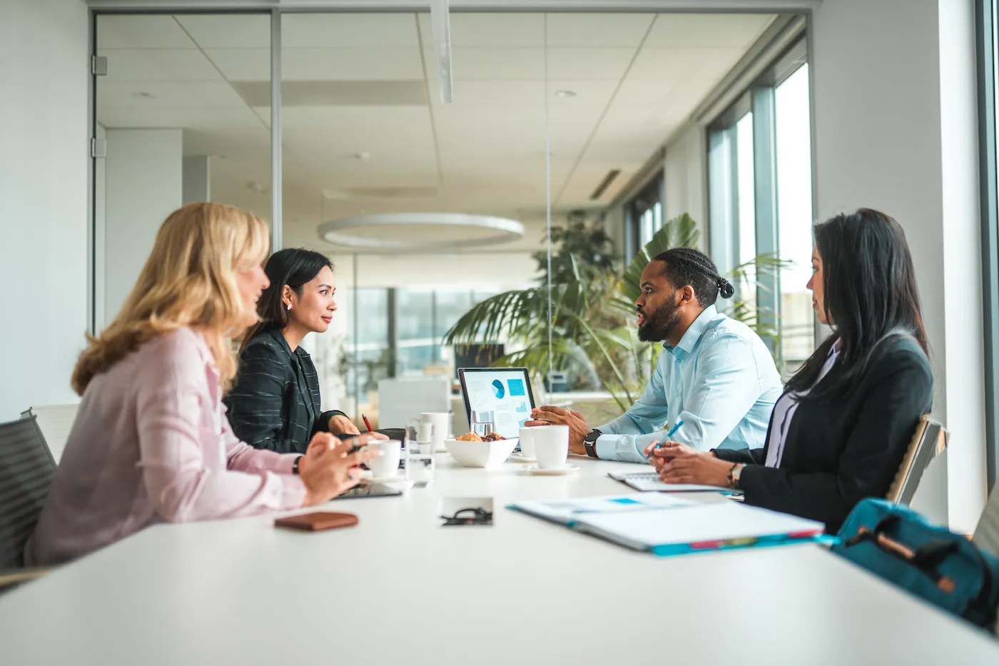 Four workers having a meeting together at a table in a conference room.